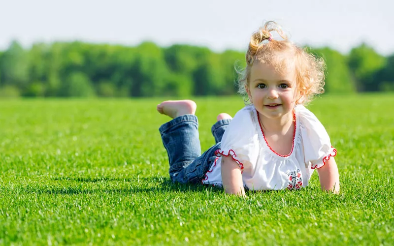 Happy kid outside enjoying green grass